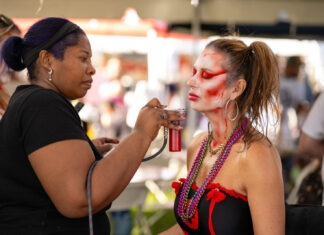 a woman getting her face painted by a man