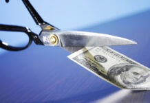 a pair of scissors cutting a hundred dollar bill