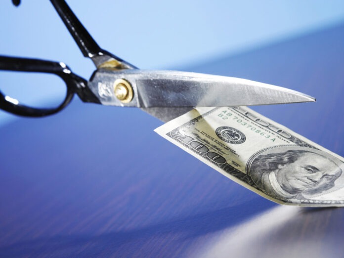 a pair of scissors cutting a hundred dollar bill