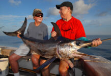 a couple of men on a boat with a big fish