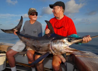 a couple of men on a boat with a big fish