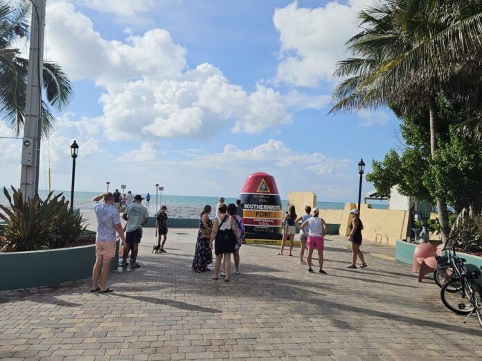 a group of people walking down a sidewalk next to the ocean