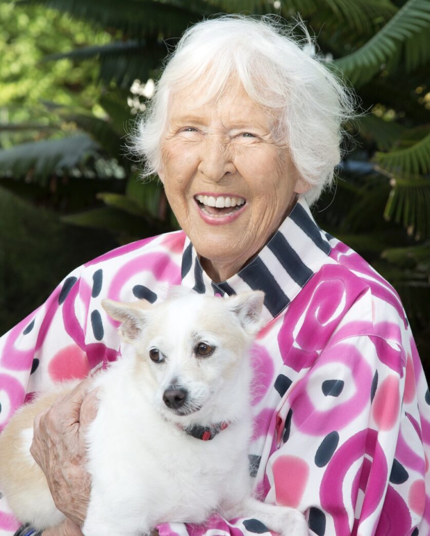 a woman holding a small white dog in her arms