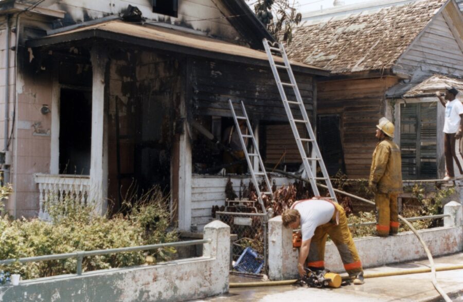 a couple of men standing in front of a fire damaged house