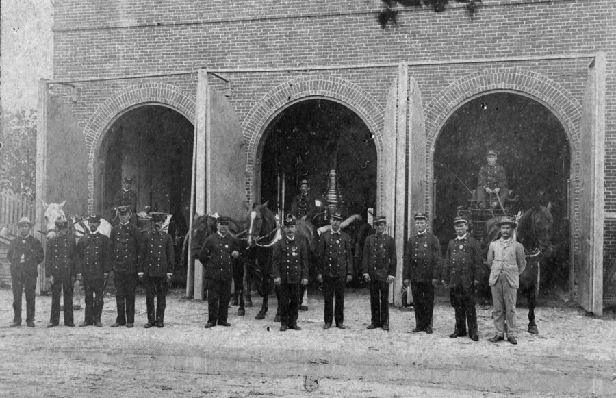 a group of men standing in front of a brick building