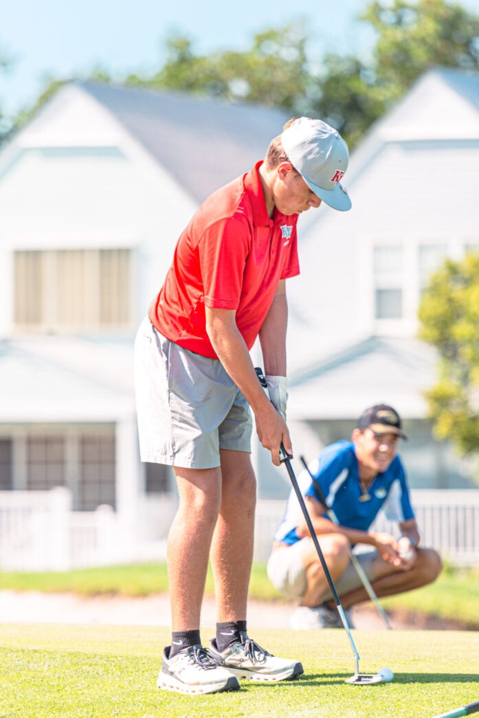 a man holding a golf club on top of a green