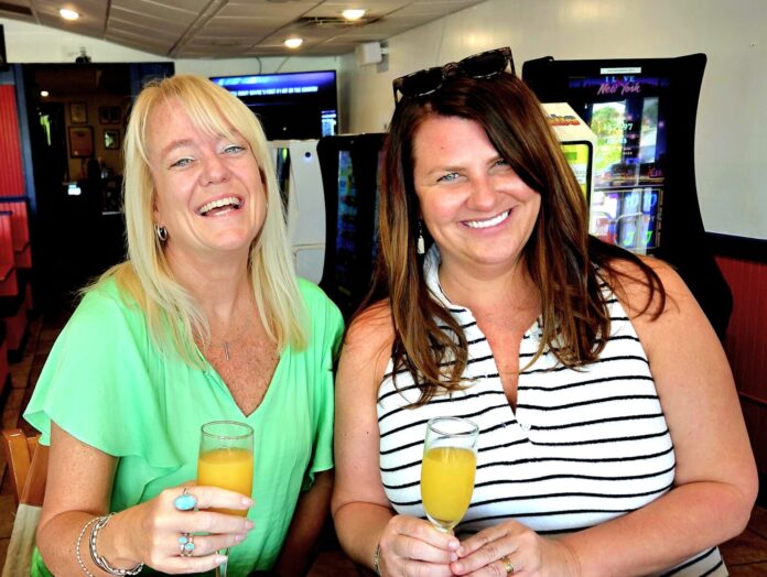 two women sitting at a table with drinks