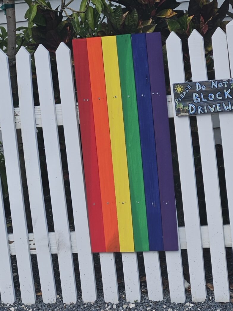 a white picket fence with a rainbow painted on it