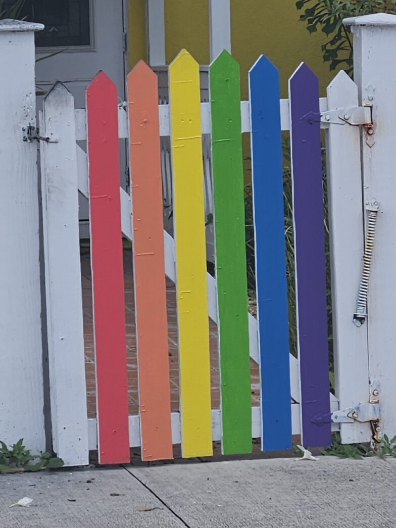 a white picket fence with a rainbow painted on it