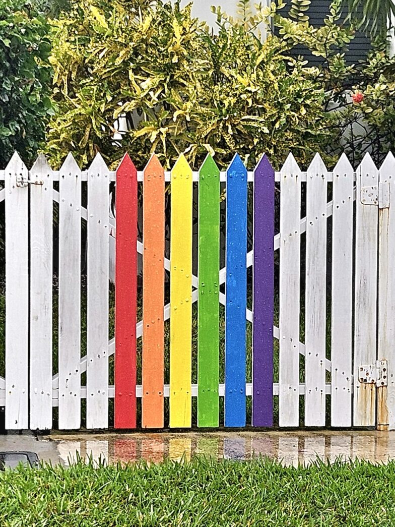 a white picket fence with a rainbow painted on it