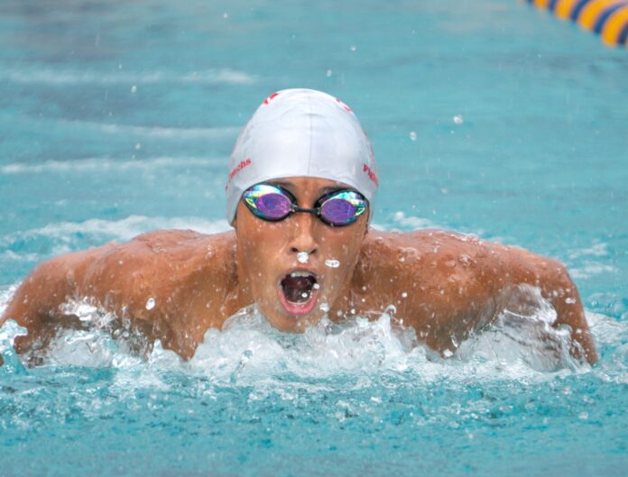 a man swimming in a pool with goggles on