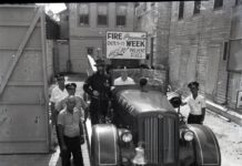 a group of men standing next to an old car
