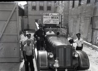 a group of men standing next to an old car