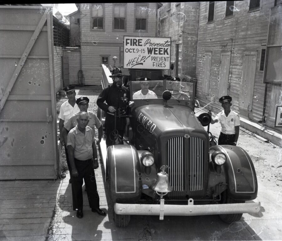 a group of men standing next to an old car