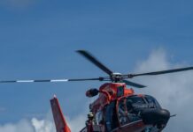 a red helicopter flying through a cloudy blue sky