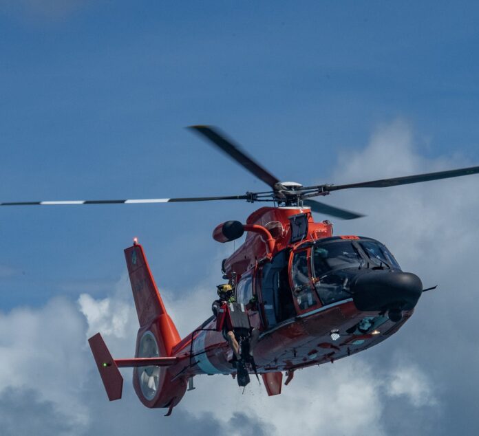 a red helicopter flying through a cloudy blue sky