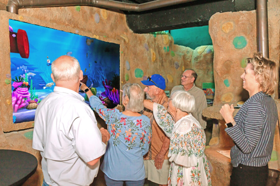 a group of people standing in front of a fish tank