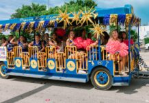 a group of people riding on the back of a blue bus