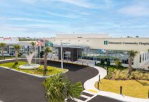 the front of a hospital with a fountain and palm trees