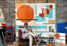 a man sitting in a chair in front of a painting