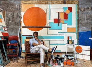 a man sitting in a chair in front of a painting