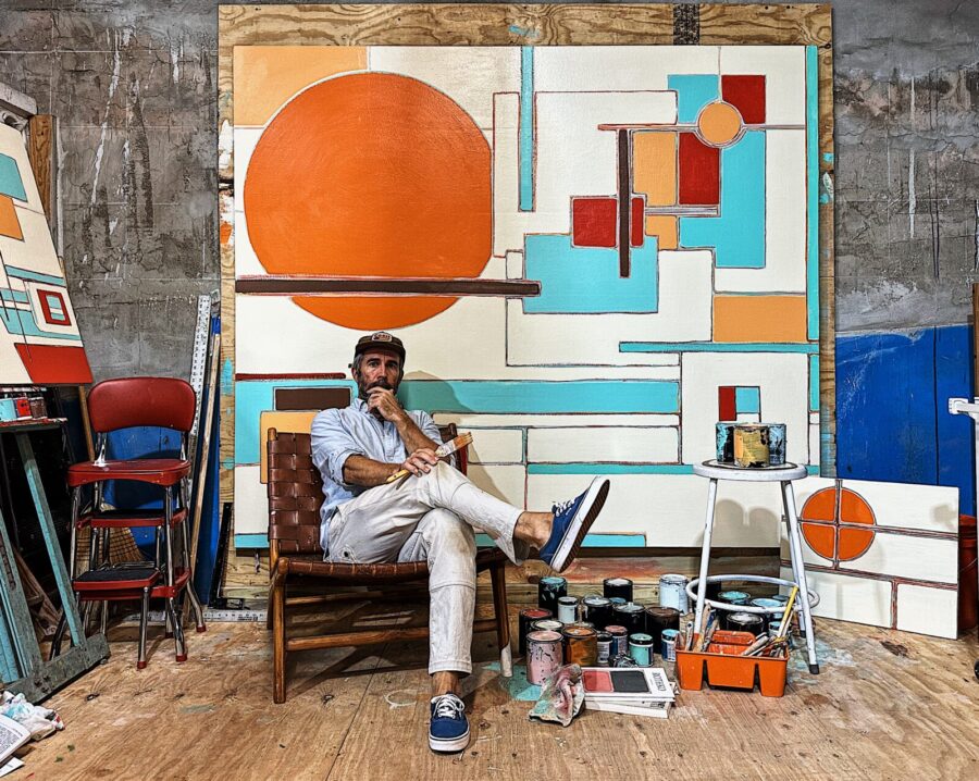a man sitting in a chair in front of a painting