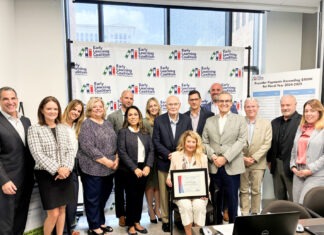 BISCEGLIA RECOGNIZED FOR DEDICATION TO LOCAL CHILDREN & FAMILIES a group of people standing in front of a poster