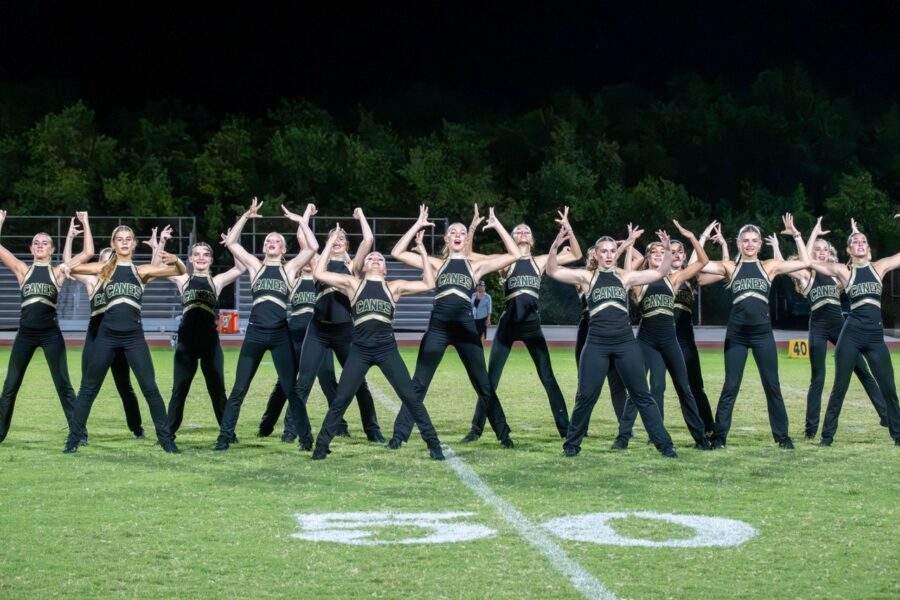a group of cheerleaders standing on a football field