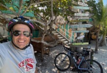 a man wearing a helmet and sunglasses standing next to a bicycle