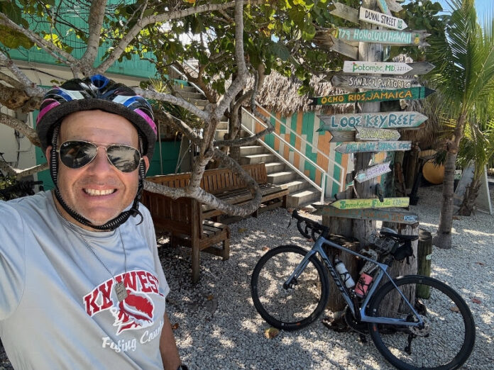 Chris Sloan with bike a man wearing a helmet and sunglasses standing next to a bicycle