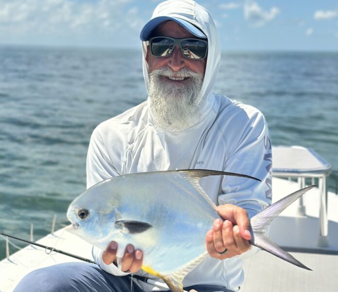 Client with permit a man sitting on a boat holding a fish