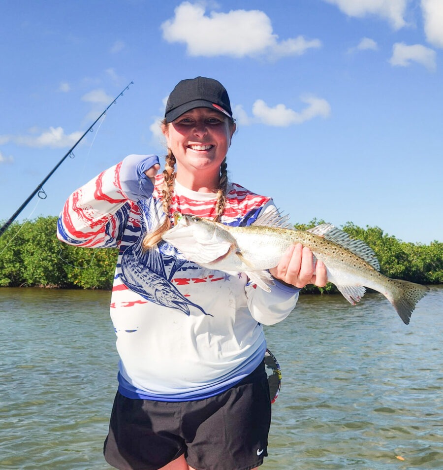 a woman holding a fish while standing on a boat