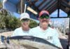 two men holding a fish on a dock