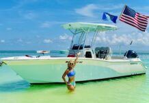 a woman standing in the water next to a boat