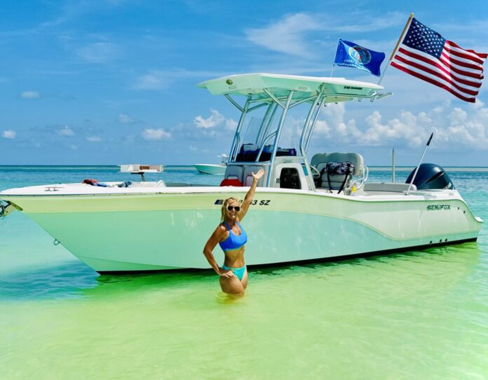 a woman standing in the water next to a boat