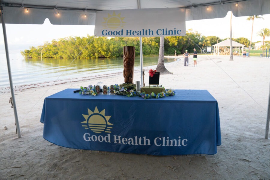 a table under a tent with a sign that says good health clinic