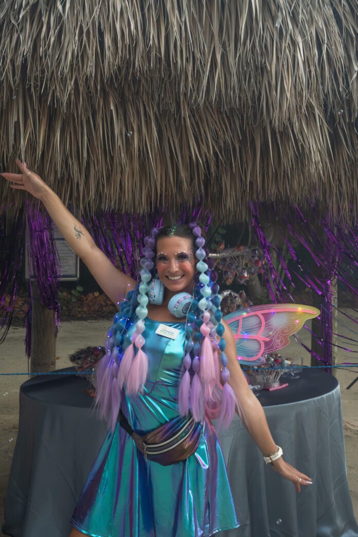 a woman in a blue dress standing in front of a tiki hut