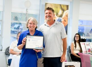 a man standing next to a woman holding an award