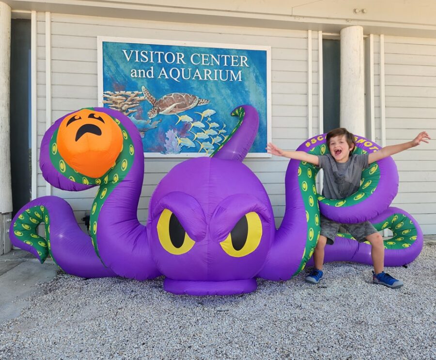 a boy sitting on an inflatable octopus in front of a building