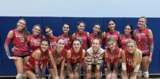 a group of women's volleyball players posing for a team photo