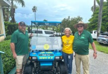 two men and a woman standing next to a golf cart