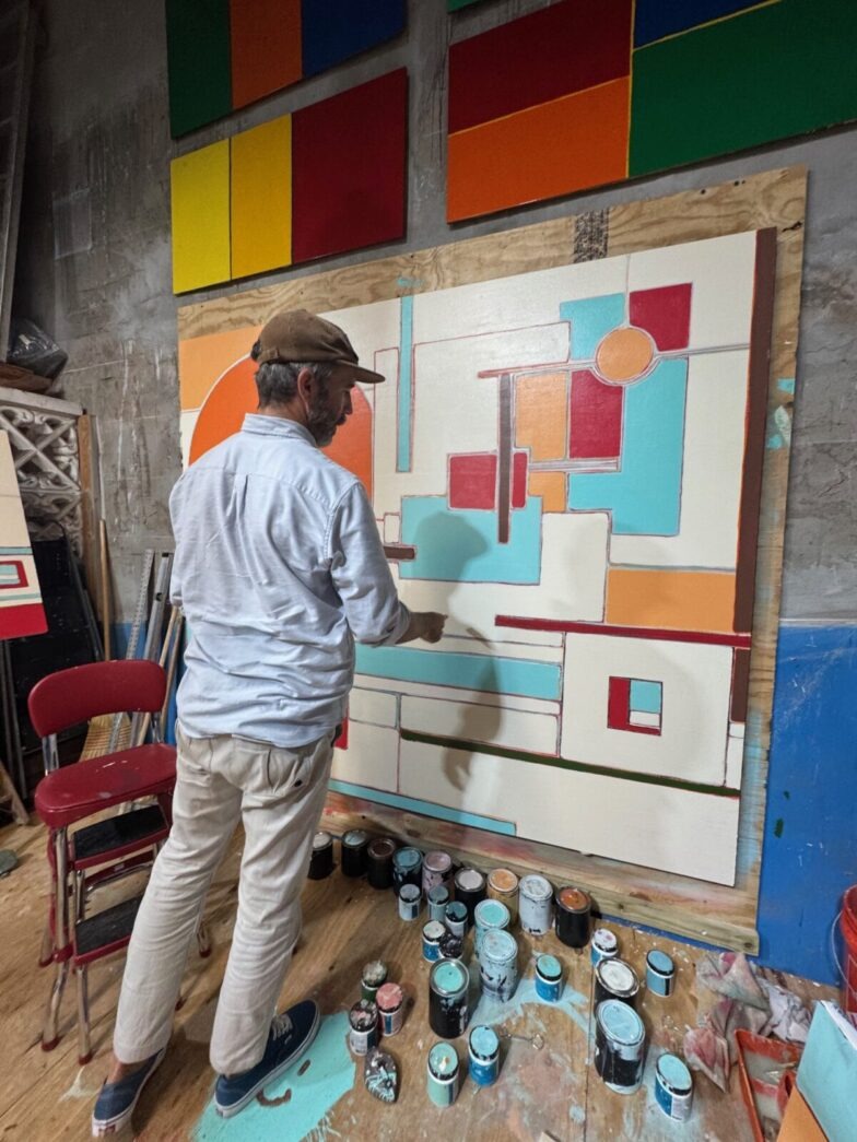 a man is painting on a wall in a room