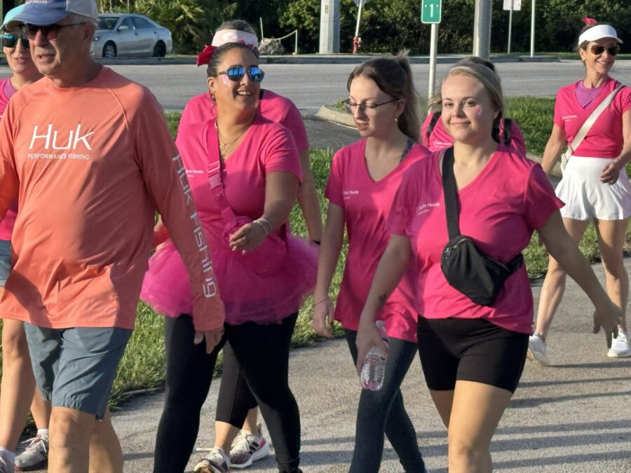 a group of people in pink shirts walking down a street