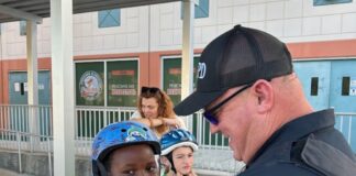 a police officer helping a young boy put on his helmet