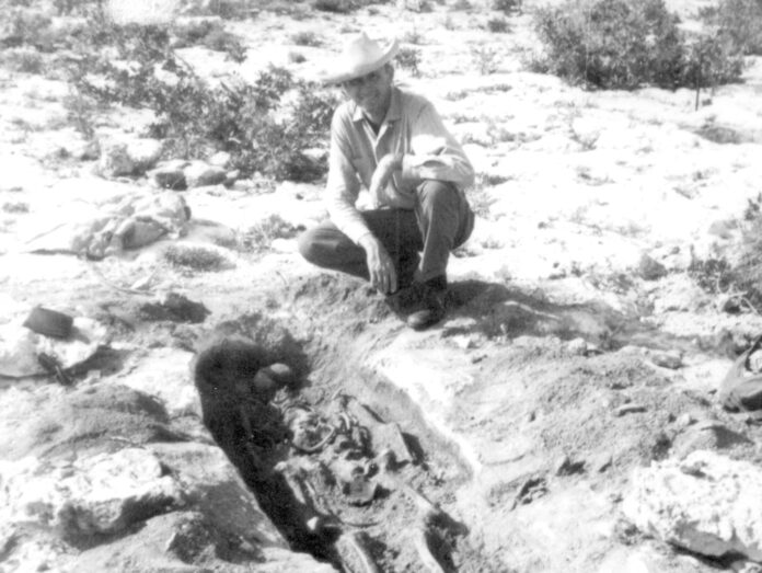 a man kneeling down next to a dead animal