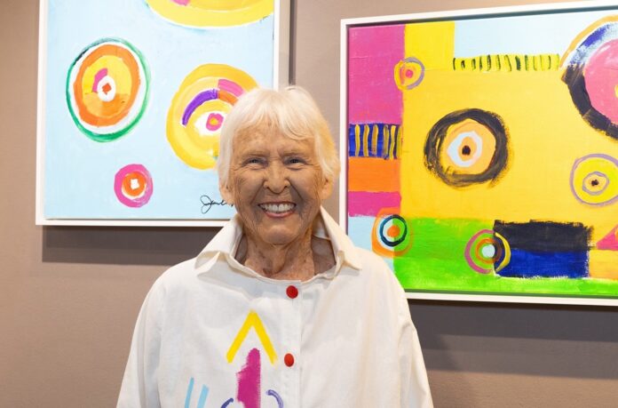 a woman standing in front of two paintings