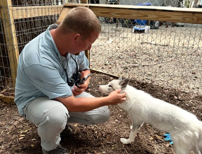 Joe Hall with Reef a man is petting a small white dog