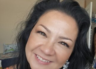 a woman with long black hair smiling at the camera
