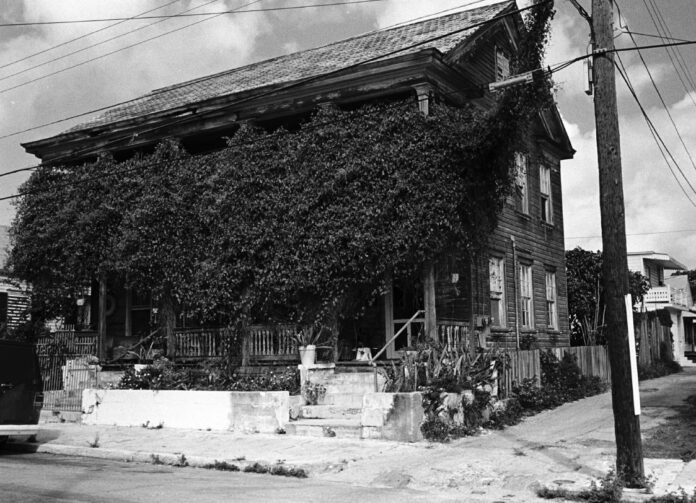 a black and white photo of a house covered in vines