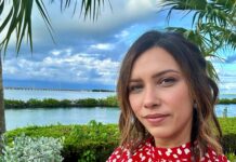 a woman in a red and white dress standing in front of a palm tree